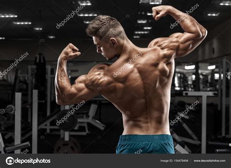 Rear View Muscular Man Posing In Gym Showing Back And Biceps Strong Male Naked Torso Working