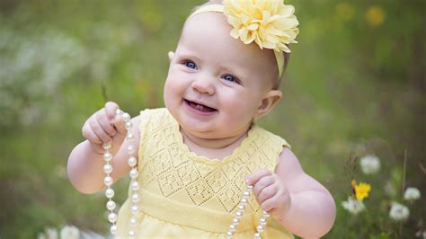 Smiley Baby Girl Child With Beads Is Wearing Yellow Dress And Headband