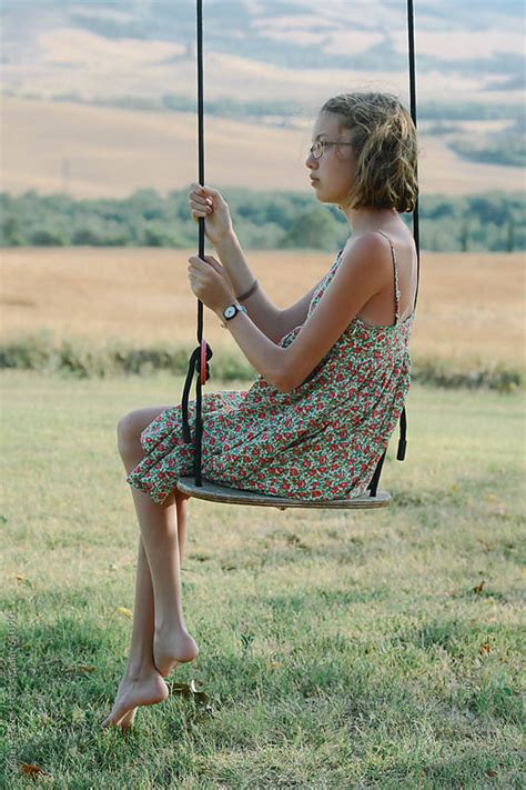 Girl Sitting On Swing With Her Legs Crossed With View Of Tuscany