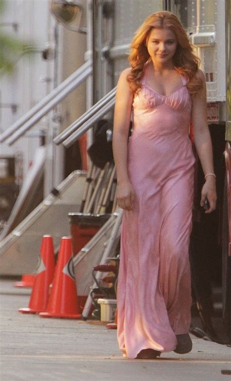 A Woman In A Pink Dress Walking Down The Street