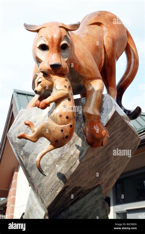 Bronze Sculpture Of A Cougar Carrying Its Cub At The Entrance To The