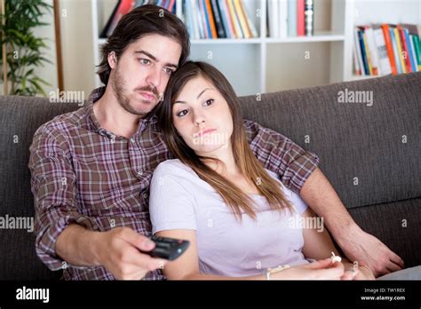 Bored Young Couple Watching Television At Home Stock Photo Alamy