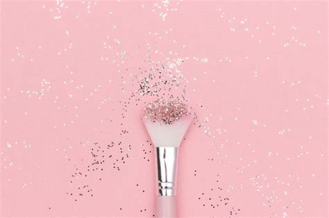 makeup brush and shiny sparkles on pastel pink festive magic makeup concept premium photo