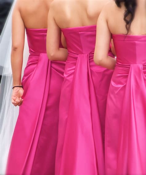 these three bridesmaids are wearing bright pink bridesmaids strapless bridesmaids dresses