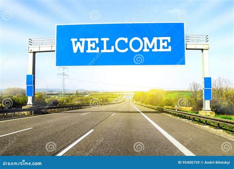 Blue Freeway Sign Over The Road On Sunny Day With Word Welcome O Stock