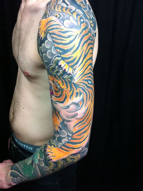 The glowing hyper real half sleeve tiger tattoo featured in the natural habitat reminds an oil painting and signifies good luck prosperity and productivity. Tiger sleeve tattoo for men full sleeve