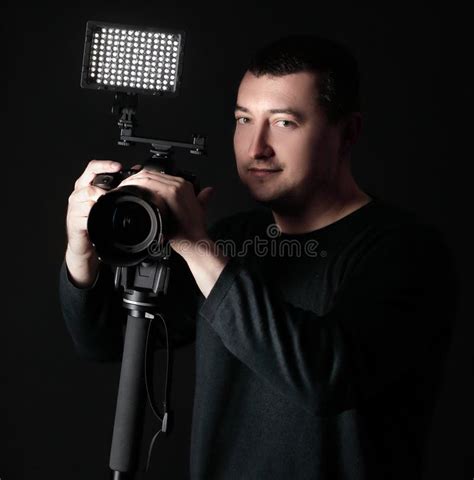 Professional Photographer With Camera On Tripodisolated On Black