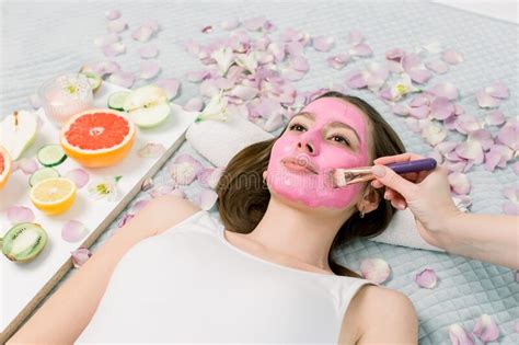 Close Up Portrait Of Beautiful Girl Applying Pink Mud Facial Mask Spa