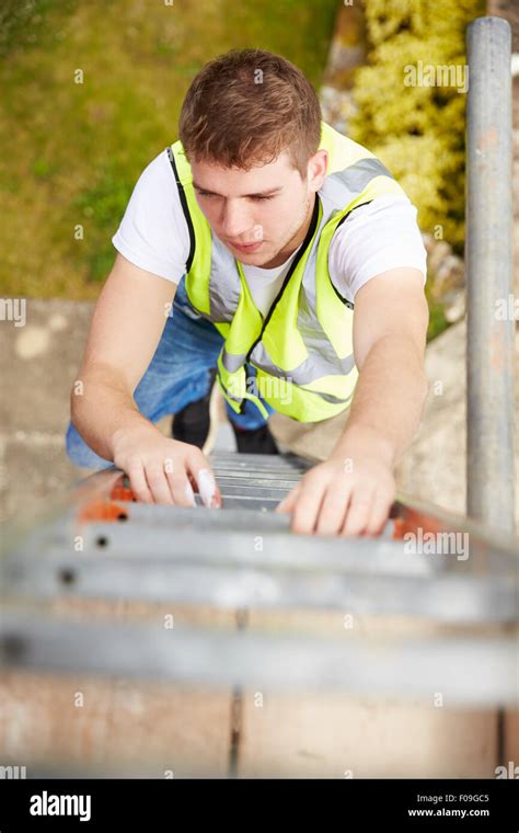 Construction Worker Climbing Ladder On Building Site Stock Photo Alamy