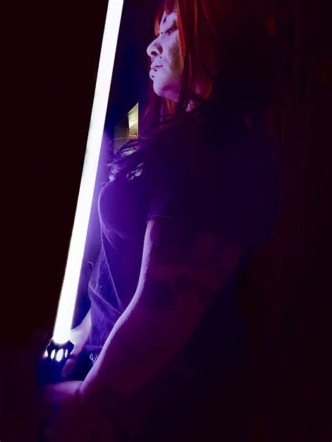 A Woman Holding A Light Saber In A Dark Room Holding An Activated