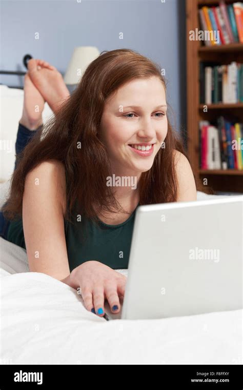 Teenage Girl Lying On Bed Using Laptop Stock Photo Alamy