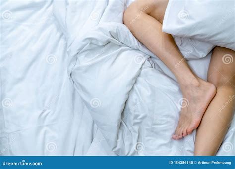 Close Up Woman Bare Feet On The Bed Over White Blanket And Bed Sheet In