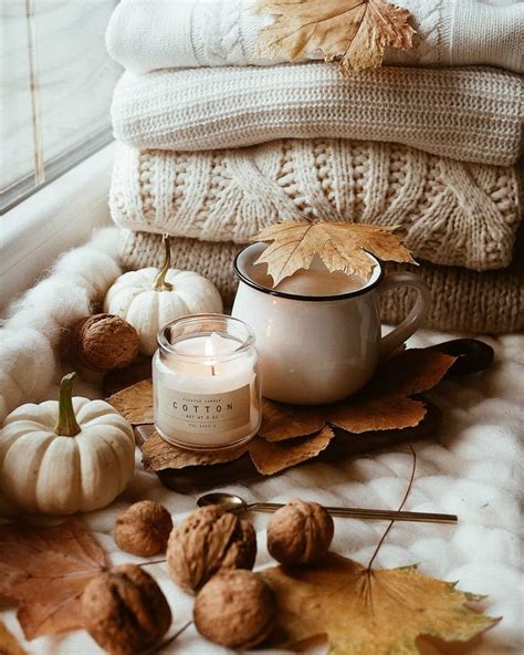 A Candle And Some Leaves On A Bed Next To Pillows Blankets And Pumpkins
