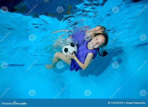 A Little Girl Playing With A Soccer Ball Underwater In The Pool On A