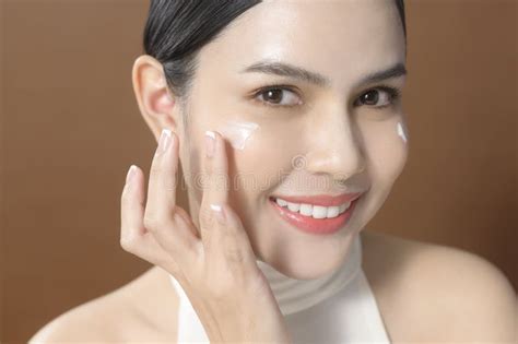 Young Woman With Beautiful Face Is Holding Cream Using Cream Of Her