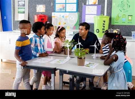 Happy Diverse Male Teacher And Children With Ecology Items In Class At