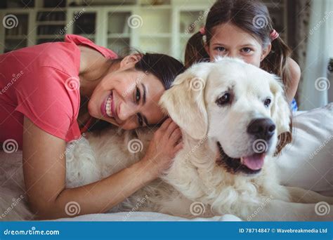 Madre E Hija Que Se Sientan Con El Perro Casero En Sala De Estar Imagen