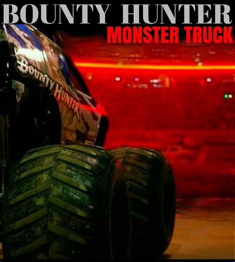 The Monster Truck Is Driving Down The Road In Front Of A Red Car With