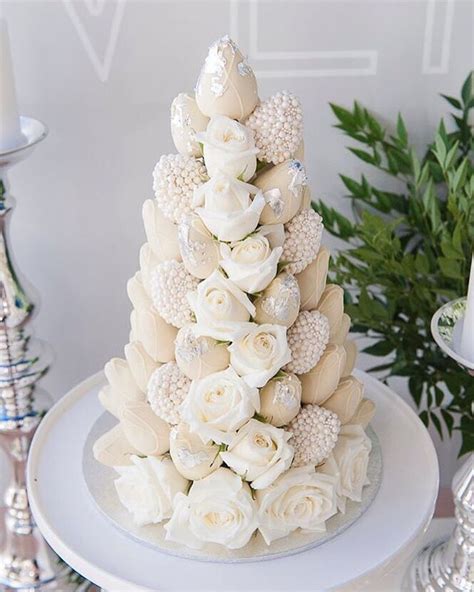 A White Wedding Cake Decorated With Flowers And Seashells On A Table