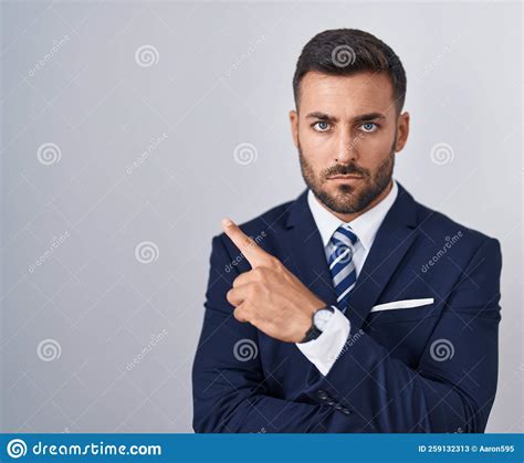 Handsome Hispanic Man Wearing Suit And Tie Pointing With Hand Finger To The Side Showing