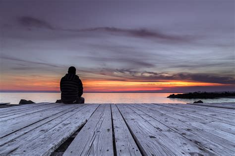 Man Sitting On The Pier And Watching The Sunset The Thayer Institute