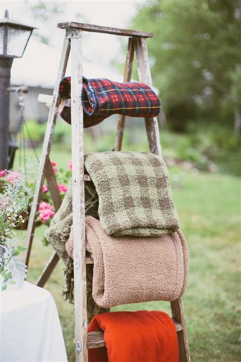 An Old Ladder With Blankets On It And Flowers In The Back Ground Near A