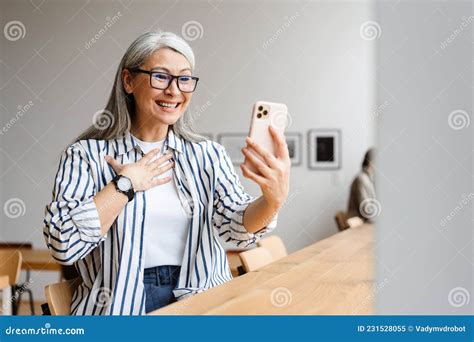 Cheerful White Haired Mature Woman Laughing And Using Cellphone Stock