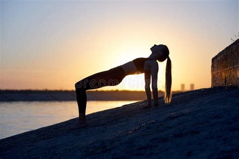 Silhouette Woman Practicing Yoga Or Stretching On The Beach Pier At