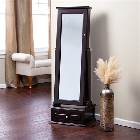 A Tall Mirror Sitting On Top Of A Wooden Floor Next To A Vase With Dry