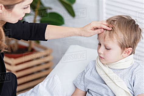 Mother Taking Care Of Sick Son And Touching His Forehead In Bedroom Stock Photo Dissolve