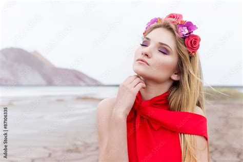 Beautiful Sexy Cute Girl With Long Blond Hair In A Long Red Evening Dress With A Wreath Of Roses