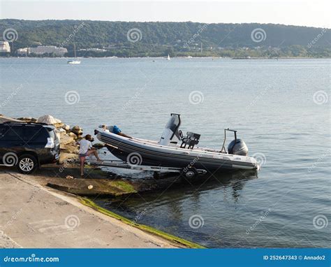 Men Pulling A Boat Onto A Car Trailer In The Seaport Editorial Stock