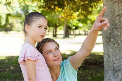 Mother Pointing At Something Besides Daughter At Park Stock Photo