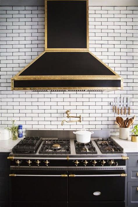 Black And Gold Range Hood On Ceiling Height Subway Tiled Wall Accented