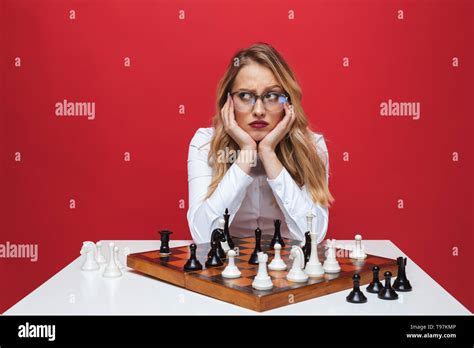 Beautiful Young Blonde Woman Wearing White Shirt Sitting At The Table Playing Chess Isolated