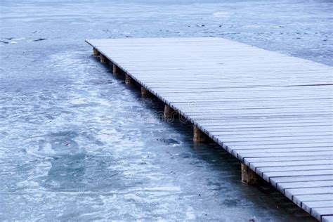 Pier On The Lake Wooden Bridge In Forest In Winter Time With Blue
