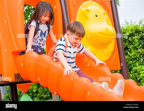 Two Kids Friends Having Fun To Play Together On Childrens Slide At