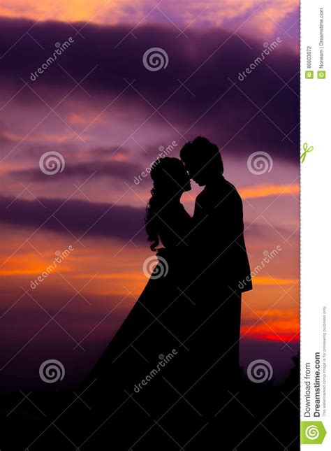 Silhouette Of Embracing Asian Bride And Groom At Sunset Stock Photo