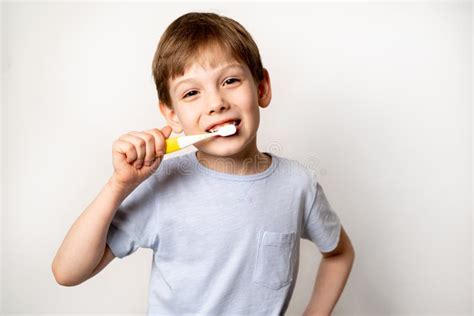 Little Boy With A Toothbrush On A White Background Brushes His Teeth