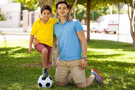 Padre E Hijo Jugando Al Fútbol En Parque A Día Soleado Banco De Fotos