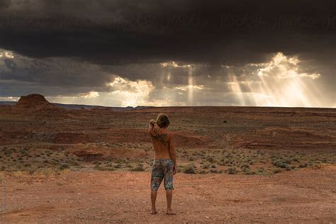 A Man Standing In The Middle Desert Watching Some Storm Clouds Roll By