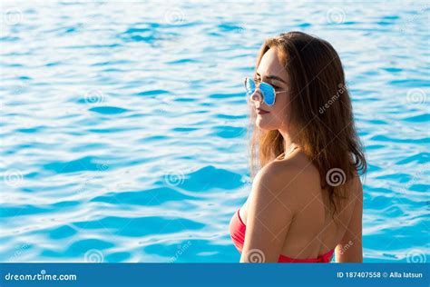 En Vacker Ung Brunettkvinna I Rosa Bikini Sitter På Baksidan Nära