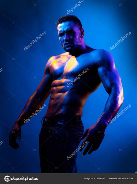 Modelo masculino sem camisa em topless Fisiculturista nu na luz de néon azul Fotografias de