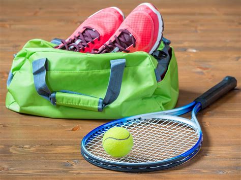 a tennis racket ball and bag sitting on the floor next to each other