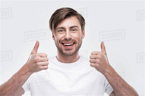 Handsome smiling man showing thumbs up, isolated on white - Stock Photo - Dissolve