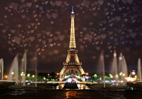 The Eiffel Tower Is Lit Up At Night With Hearts Floating In The Air