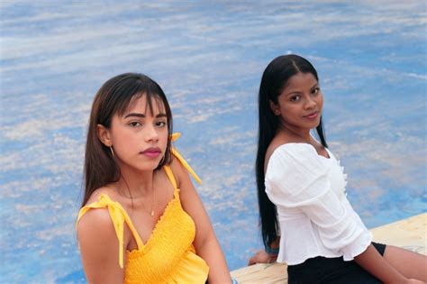 Dos Amigas Latinas Sentadas En El Parque Mirando A La Cámara Foto Premium