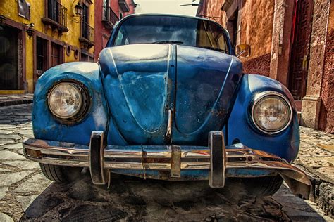 Vintage Blue Volkswagen Beetle Parked On Road In Front Of Lake With