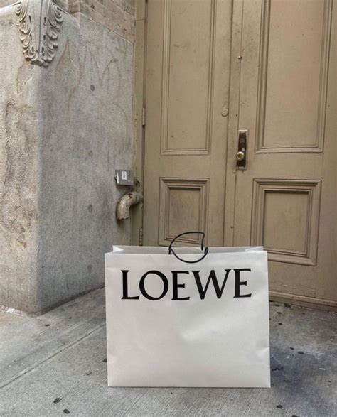 A White Bag Sitting On The Ground In Front Of A Door That Says Loewe