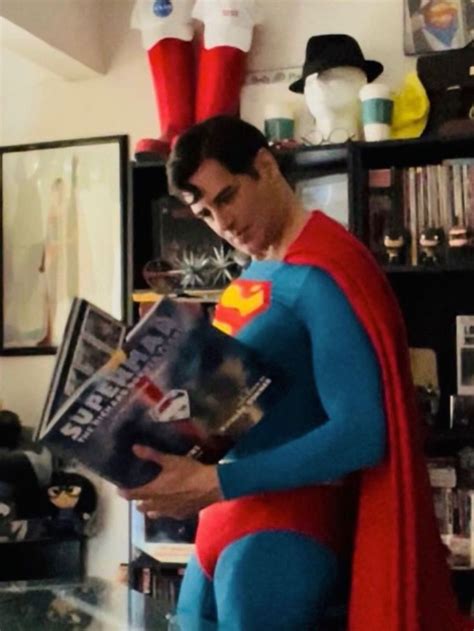 A Man Dressed As Superman Reading A Magazine